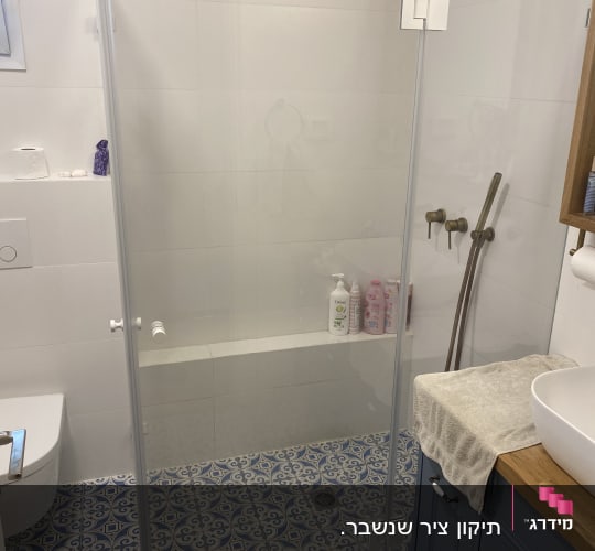 מקלחת עם דלת זכוכית, כיור ואריחים מעוצבים